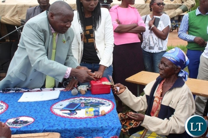 TAMANDENJI Zulu, receives money from Lundazi District Education Board Secretary, Chiza Mtonga, during the payment of the Social Cash Tranfer funds to beneficiaries in Mnyamazi ward of Lundazi Central constituency in Lundazi