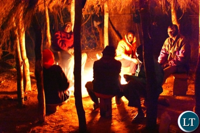 Men In the village sitting and chatting at the mphala in the evening around the fire.