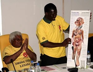 Dr. Fastone Goma of UNZA displays a placard on the effects of smoking during the launch of the smoke free Lusaka campaign while Dr. Lambert looks on.